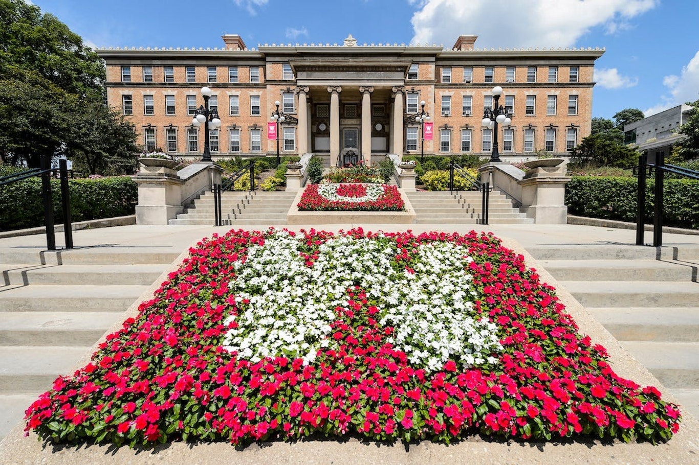Contrasting red and white flowers form the letters U and W in flowerbeds leading to the entrance of Agricultural Hall at the University of Wisconsin-Madison during summer